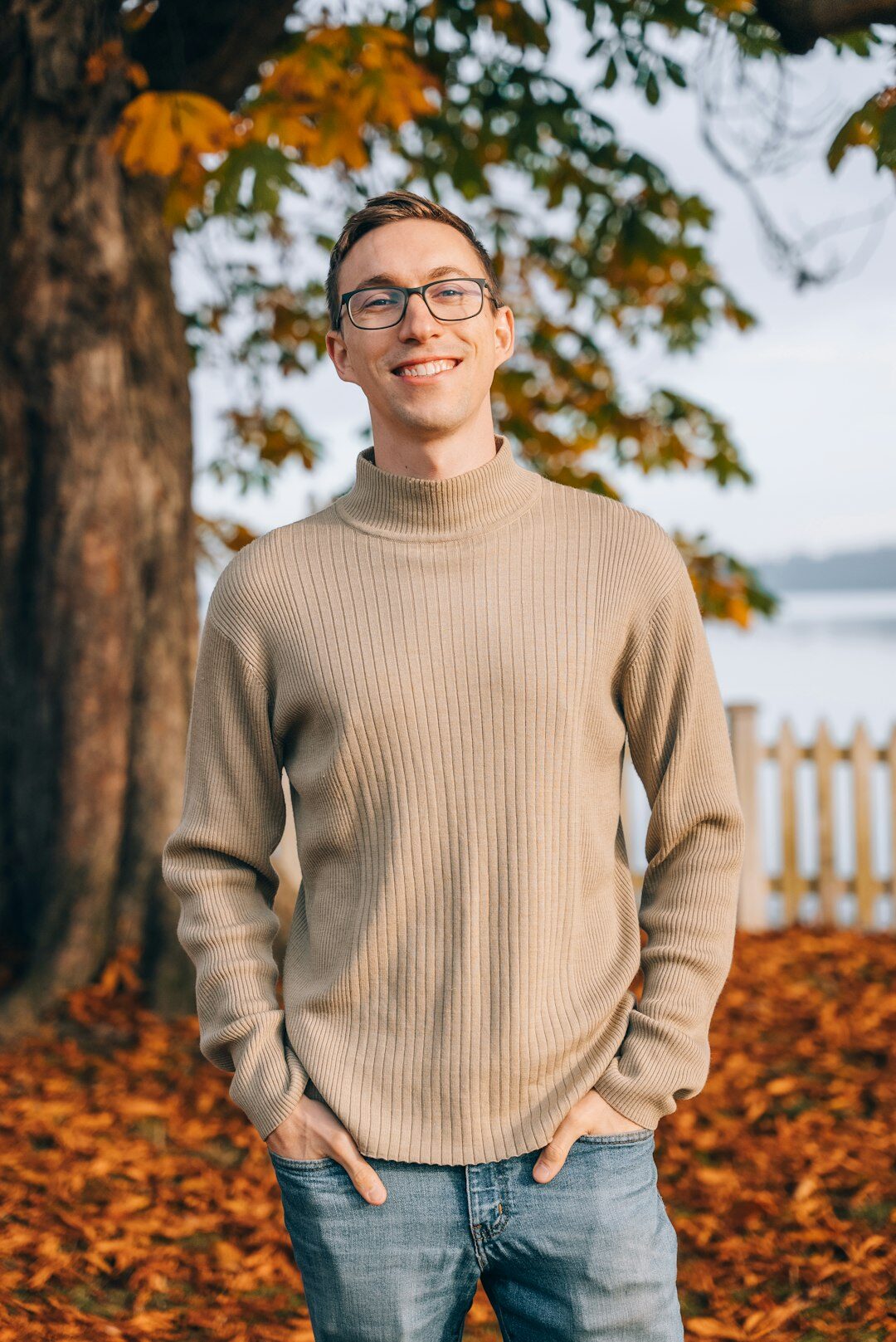 Studio portrait of a European male editor in his fifties wearing glasses and a knit sweater